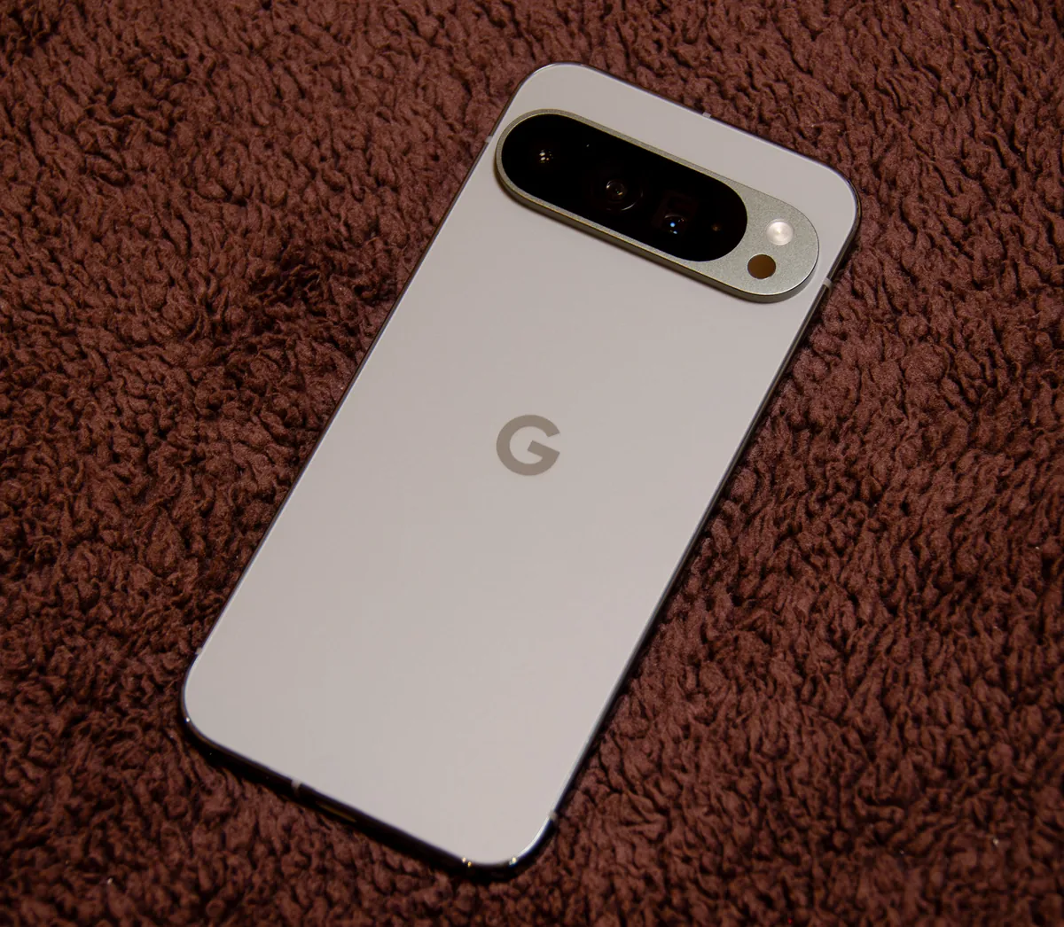Google Pixel 9 Pro XL in Hazel, back view, lying on a brown rug